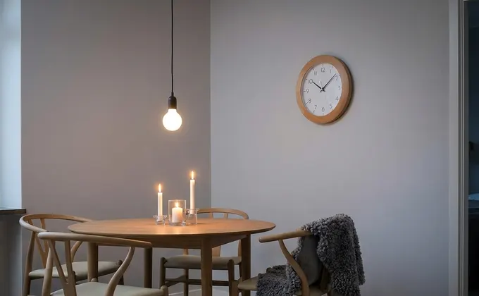 Coin repas scandinave avec chaises en bois et éclairage tamisé pour le dîner.